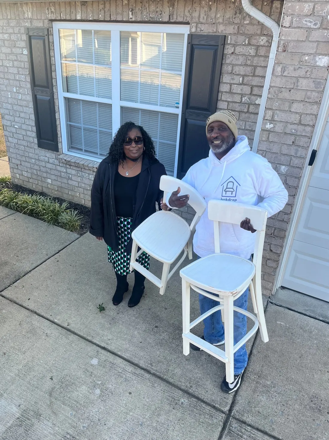 A Junkdrop team member and a Nashville neighbor smiling together with two chairs outside a home