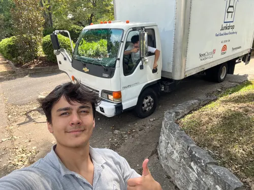 A smiling Junkdrop crew member giving a thumbs-up beside the truck